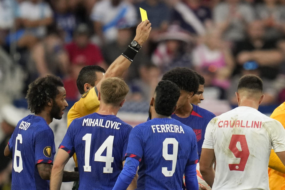 Canada forward Lucas Cavallini (9) receives a yellow card for tripping against the United States during a CONCACAF Gold Cup semi-final soccer match, Sunday, July 9, 2023, in Cincinnati. (AP Photo/Michael Conroy)