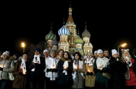 Participants of a performance marking Earth Hour hold candles as they commemorate the victims of the crashed Boeing 737-800 flight FZ981 operated by Dubai-based budget carrier Flydubai, near St. Basil's Cathedral in central Moscow, Russia, March 19, 2016. REUTERS/Maxim Zmeyev