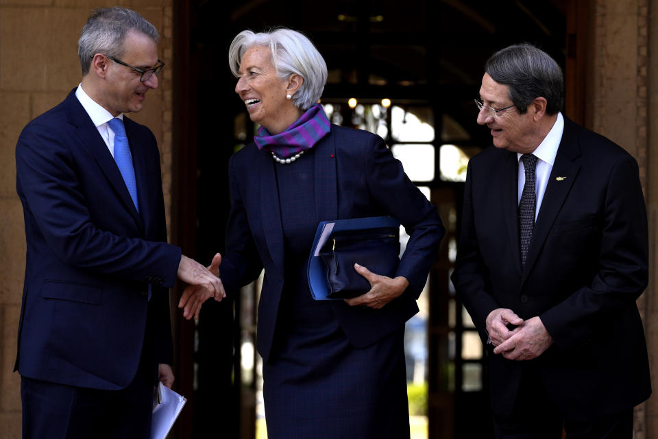 Cyprus President Nicos Anastasiades, right, looks the President of the European Central Bank Christine Lagarde as she shakes hands with Governor of Central Bank of Cyprus Constantinos Herodotou before their meeting at Presidential Palace in the capital Nicosia, Cyprus, Wednesday, March 30, 2022. Lagarde is visiting European Union member Cyprus amid the country's continuing efforts to buttress its banking system following a 2013 financial crisis that nearly brought the island nation to bankruptcy. (AP Photo/Petros Karadjias)