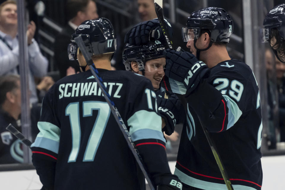 Seattle Kraken forward Eeli Tolvanen, center, is congratulated by defenseman Vince Dunn, right, and forward Jaden Schwartz after scoring a goal during the second period of an NHL hockey game against the New York Islanders, Sunday, Jan. 1, 2023, in Seattle. (AP Photo/Stephen Brashear)