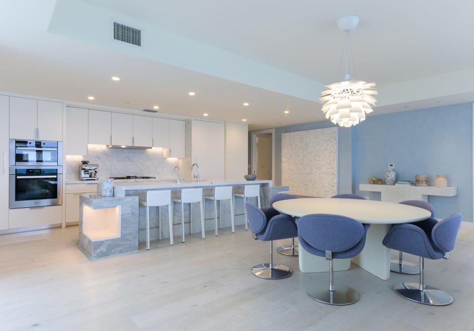 A bar-height counter and work island separates the marble-appointed kitchen from the dining area and the rest of the great room.