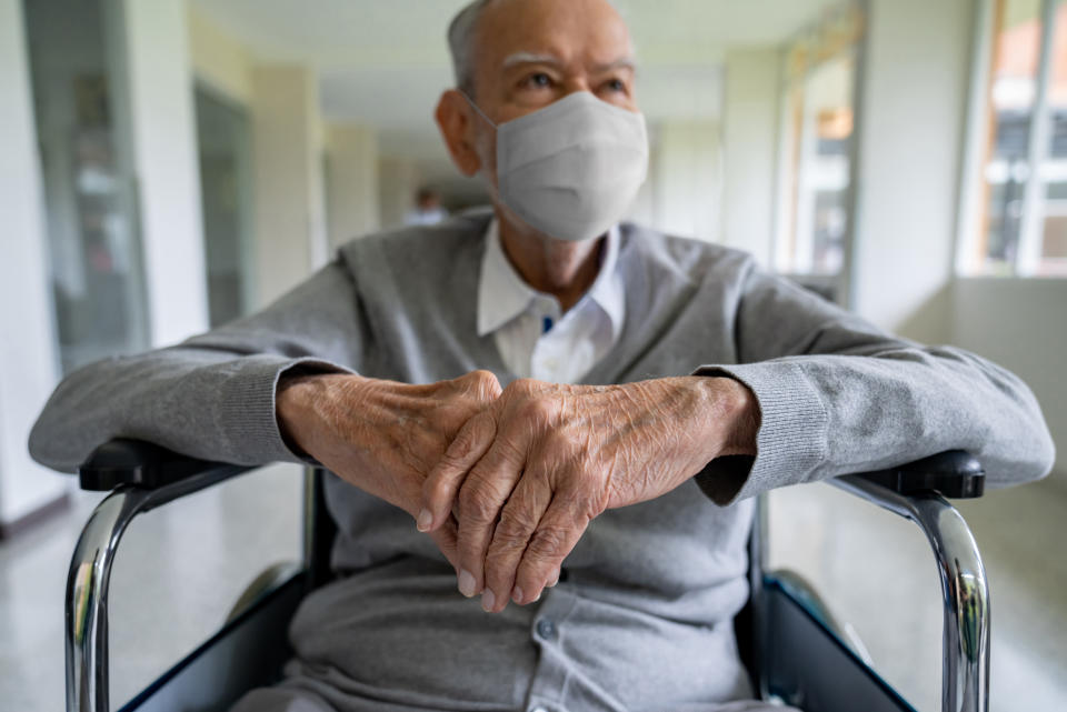 Senior adult in a wheelchair at the hospital wearing a facemask to avoid coronavirus â pandemic lifestyle concepts
