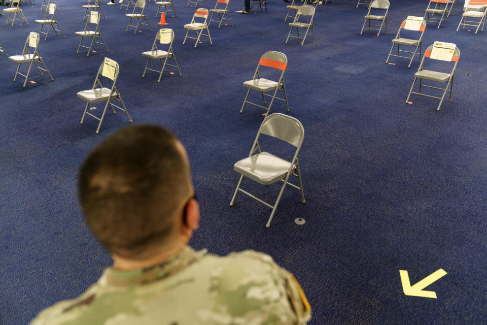 Rhode Island Army National Guard Sgt. Juan Gomez looks over the post inoculation waiting area at a coronavirus mass-vaccination site at the former Citizens Bank headquarters in Cranston, R.I., Thursday, June 10, 2021. The U.S. is confronted with an ever-growing surplus of COVID-19 vaccines, looming expiration dates and stubbornly lagging demand at a time when the developing world is clamoring for doses to stem a rise in infections. (AP Photo/David Goldman)