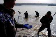 FILE PHOTO: A fisherman holds a copper coin found in debris by a dwindling river that feeds the Poyang lake, China