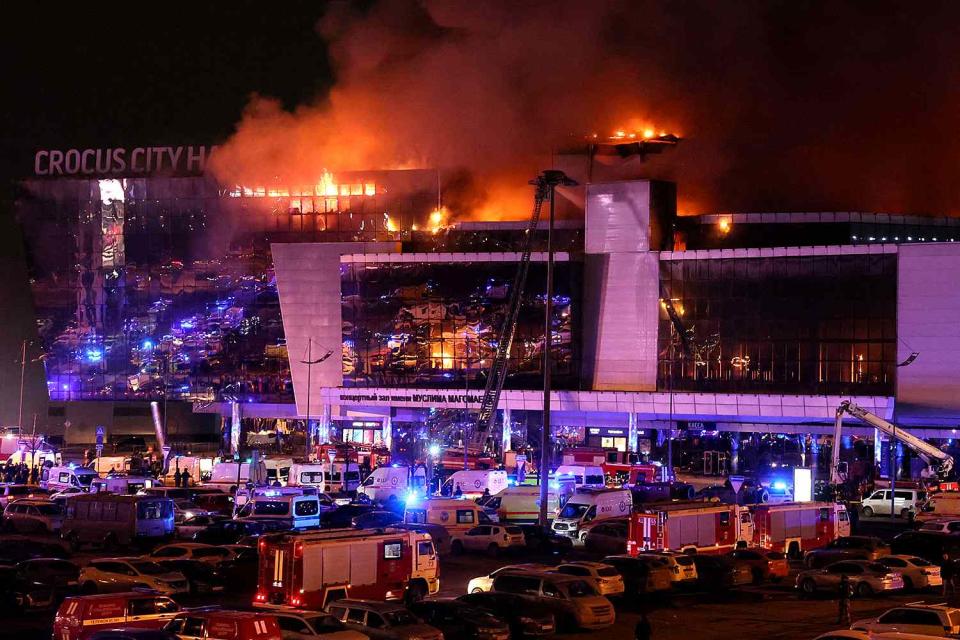 <p>STRINGER/AFP via Getty</p> Emergency services vehicles are seen outside the burning Crocus City Hall concert hall 