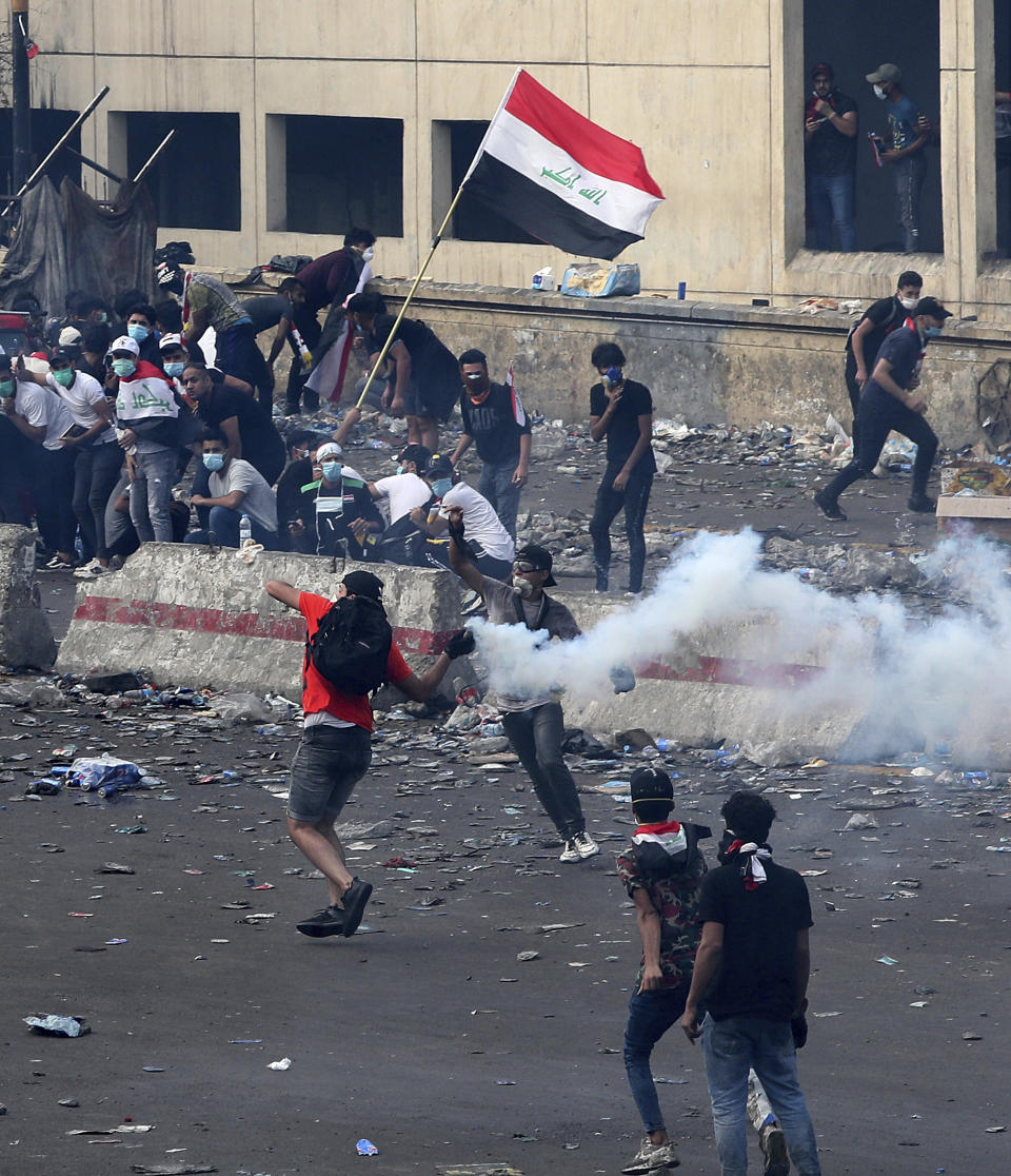 An anti-government protester prepares to throw a tear gas canister fired by Iraq security forces during a demonstration, in Baghdad, Iraq, Monday, Oct. 28, 2019. Protests have resumed in Iraq after a wave of anti-government protests earlier this month were violently put down. (AP Photo/Hadi Mizban)