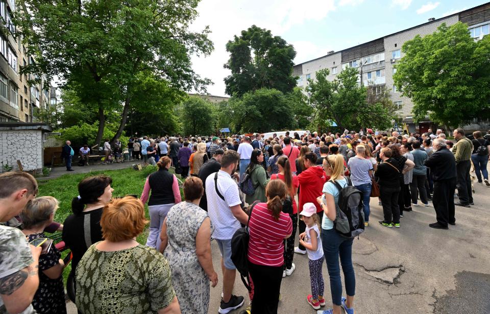 People queue as they wait for humanitarian aid in the town of Bucha, north-west from Ukrainian capital of Kyiv on June 3, 2022 on the 100th day of the Russian invasion of Ukraine.
