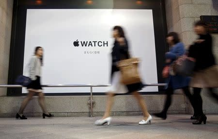 Pedestrians walk past an advertisement board for Apple Watch outside the Isetan department store, where an Apple Watch store will be located, in Tokyo April 9, 2015, a day before the shop opens and starts accepting reservations for the Apple Watch. REUTERS/Yuya Shino