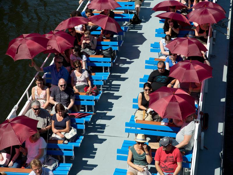 Fahrgäste eines Ausflugsbootes auf der Spree schützen sich mit Schirmen vor der niederbrennenden Sonne. In den kommenden Tagen wird es noch heißer. Foto: Jörg Carstensen