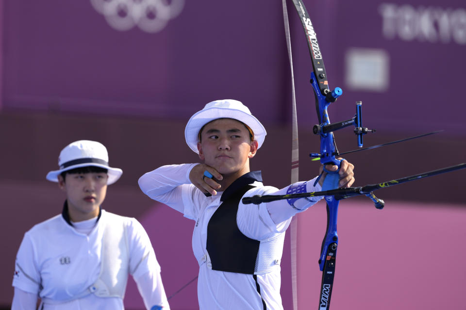 South Korea's Kim Je Deok releases an arrow flanked by his teammate An San during the mixed team competition at the 2020 Summer Olympics, Saturday, July 24, 2021, in Tokyo, Japan. (AP Photo/Alessandra Tarantino)