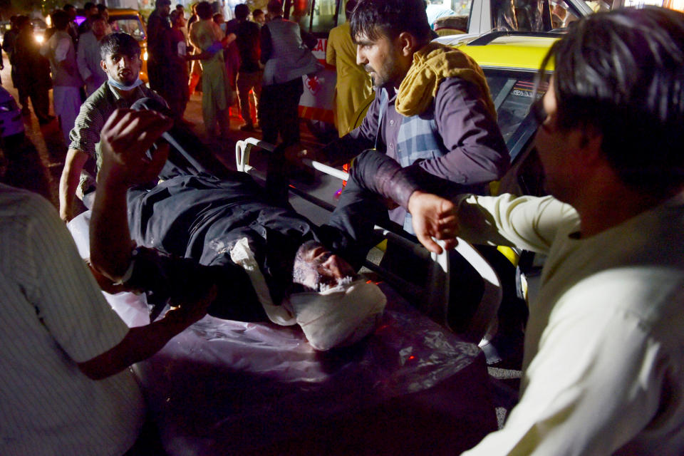 Image: Medical and hospital staff bring an injured man on a stretcher for treatment after two blasts outside the airport in Kabul on Aug. 26, 2021. (Wakil Koshar / AFP - Getty Images file)