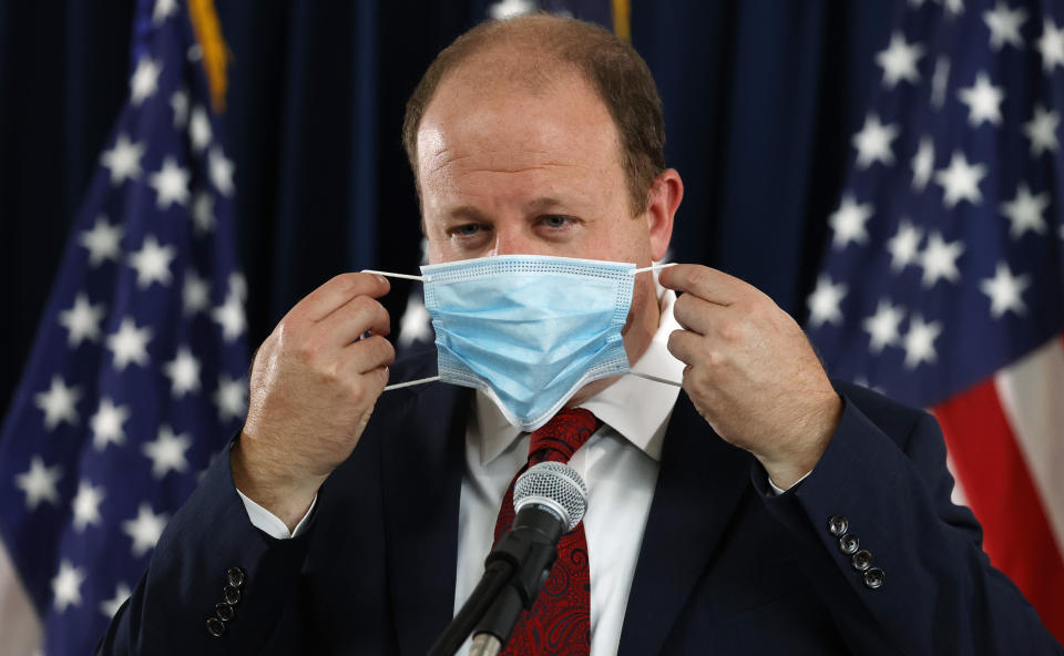 Colorado Governor Jared Polis puts on his face mask after concluding a news conference on the state's efforts against the new coronavirus Tuesday, July 21, 2020, in Denver. (AP Photo/David Zalubowski)