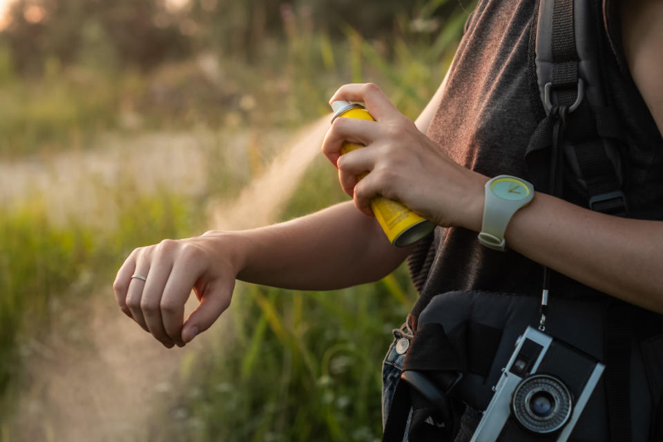 Close-up of young female backpacker tourist applying bug spray on hands