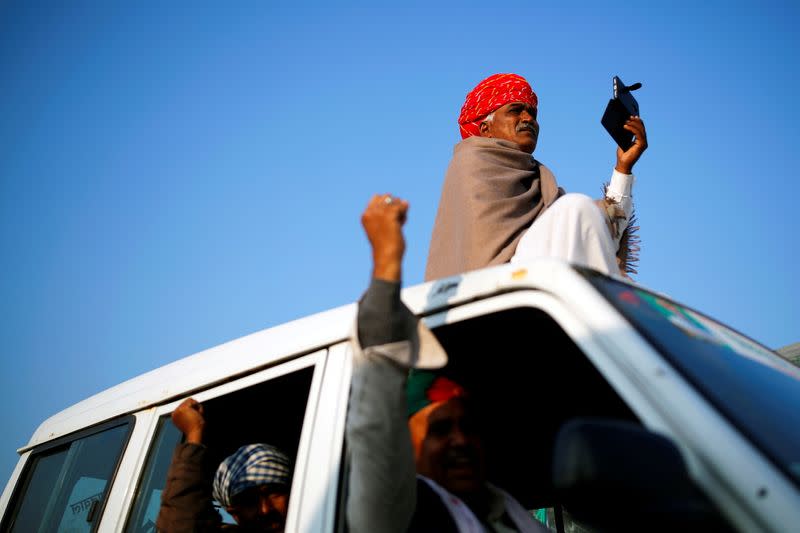 A farmer sits on a vehicle as others gesture at the site of a protest against new farm laws at a state border on a national highway, in Shahjahanpur