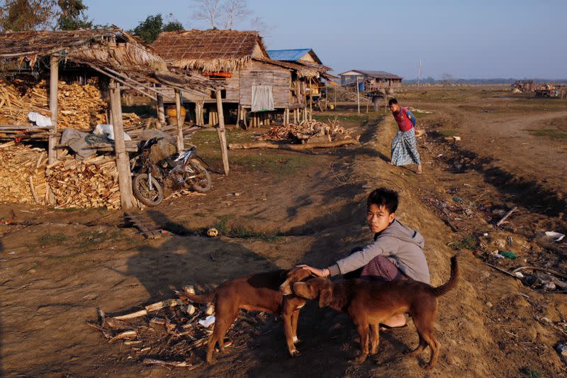 A boy from Ta Dar U village pets a dog after villagers relocated their houses inland in Bago, Myanmar