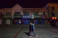 People wearing face masks walk past closed shops in the city centre of Suifenhe, a city of Heilongjiang province on the border with Russia, as the spread of the coronavirus disease (COVID-19) continues in the country