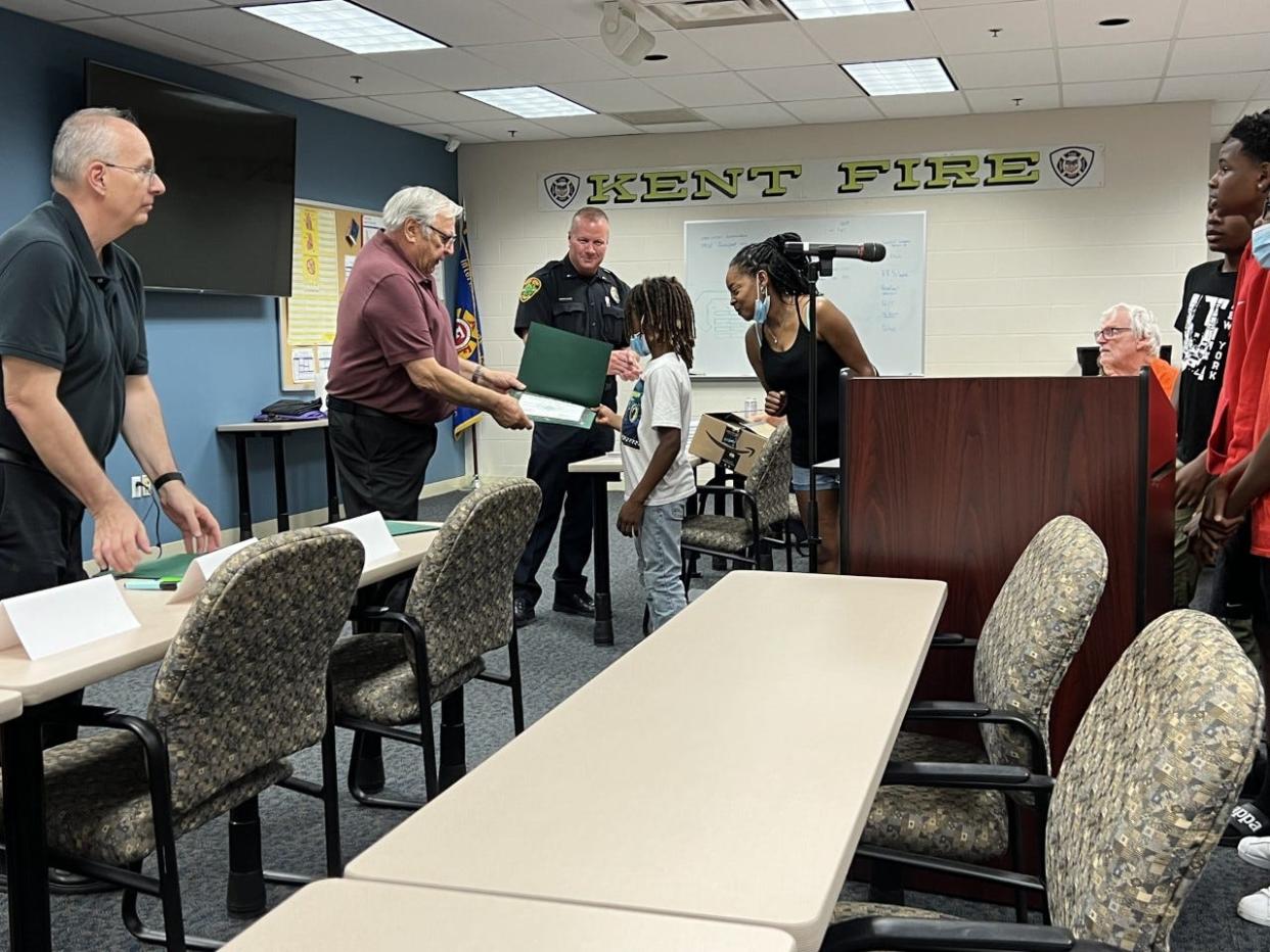 Antwan Mack, one of the boys who lifted a tractor and a man who was trapped in front of a home in Kent, and others who helped are honored at a Kent City Council meeting.