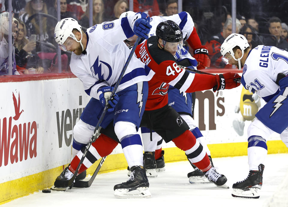 New Jersey Devils Brian Halonen (48) battles Tampa Bay Lightning defenseman Erik Cernak (81) and center Luke Glendening (11) for the puck during the second period of an NHL hockey game, Sunday, Feb. 25, 2024, in Newark, N.J. (AP Photo/Noah K. Murray)