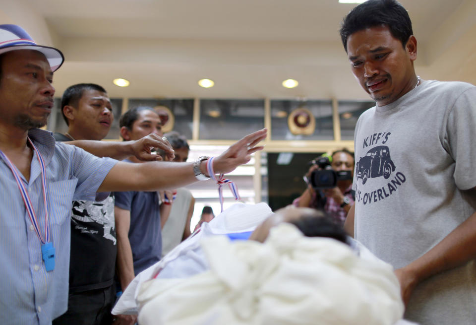 Friends and relatives of Prakong Chuchan, a protester who was killed in Friday's bomb blast, cry over his body before a memorial service at Rama hospital in Bangkok, Thailand Sunday, Jan. 19, 2014. On Friday, a grenade hurled at a crowd of marching demonstrators in another part of Bangkok killed one man and wounded dozens of people, police said. (AP Photo/Wason Wanichakorn)