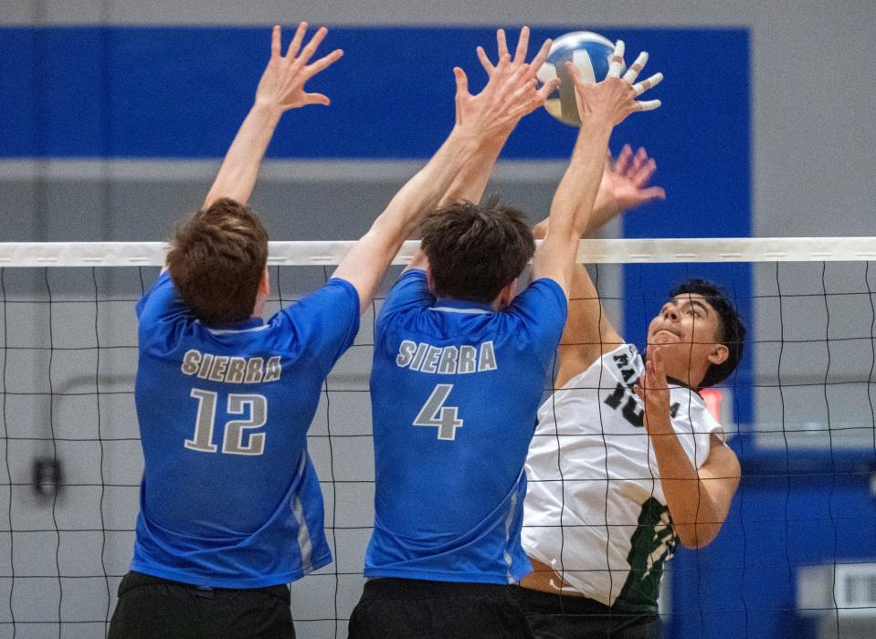 Manteca's Garrison Reis, right, spikes the ball on Sierra's Owen Altadonna, left, and Landon West during a boys varsity volleyball game at Sierra High in Manteca on Apr. 17, 2024.