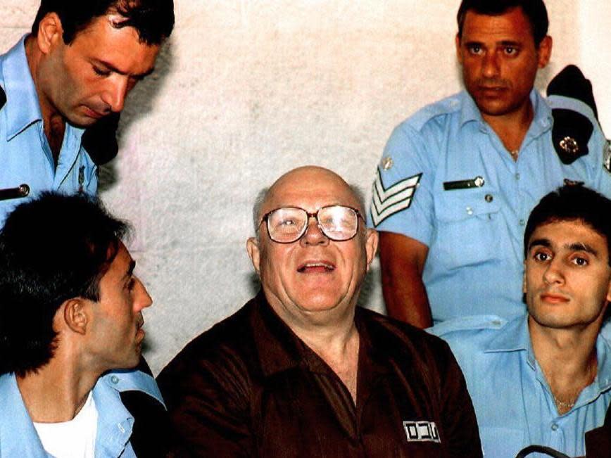 John Demjanjuk surrounded by guards at his Israeli trial for war crimes: Getty