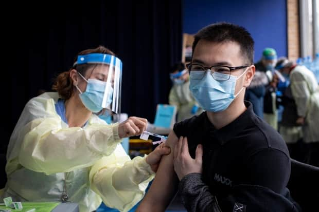 A person receives a COVID-19 vaccine in Toronto. The city is running at least one vaccination clinic in each of the city’s 25 wards on Saturday in a bid to encourage more folks to get vaccinated against COVID-19. (Evan Mitsui/CBC - image credit)