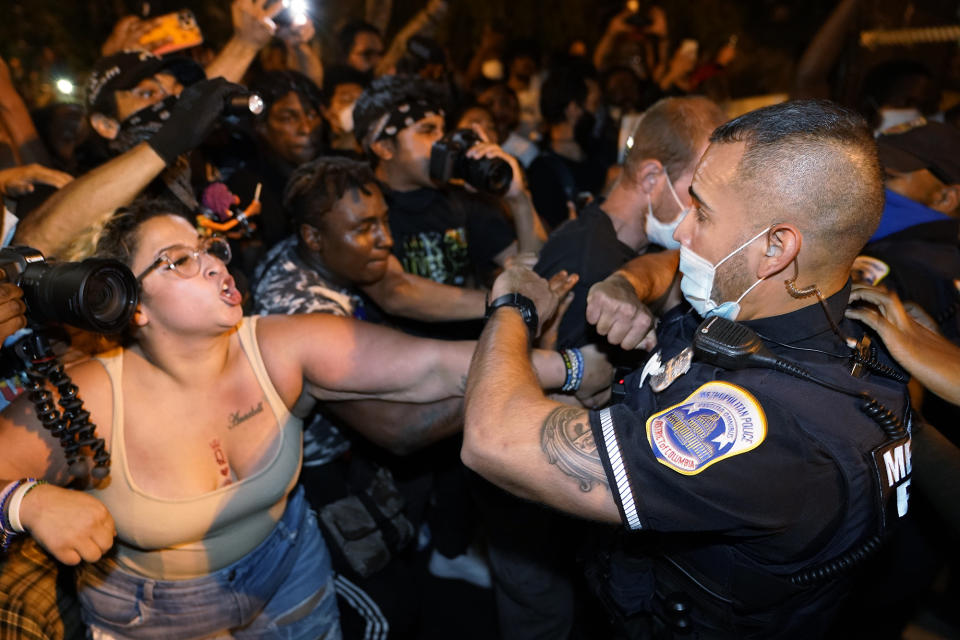 Metropolitan Police are confronted by protestors as police carry away a handcuffed protestor along a section of 16th Street, Northwest, renamed Black Lives Matter Plaza, Thursday night , Aug. 27, 2020, in Washington, after President Donald Trump had finished delivering his acceptance speech from the White House South Lawn. (AP Photo/Julio Cortez)