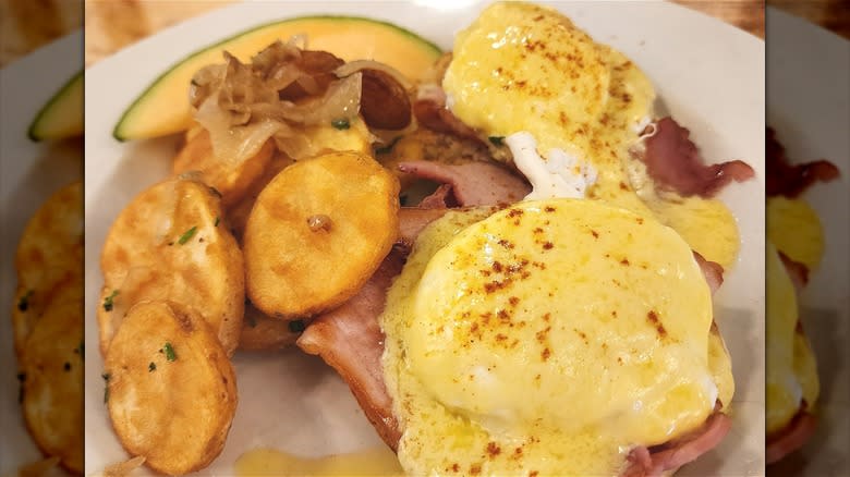 Eggs Benedict with potatoes fruit