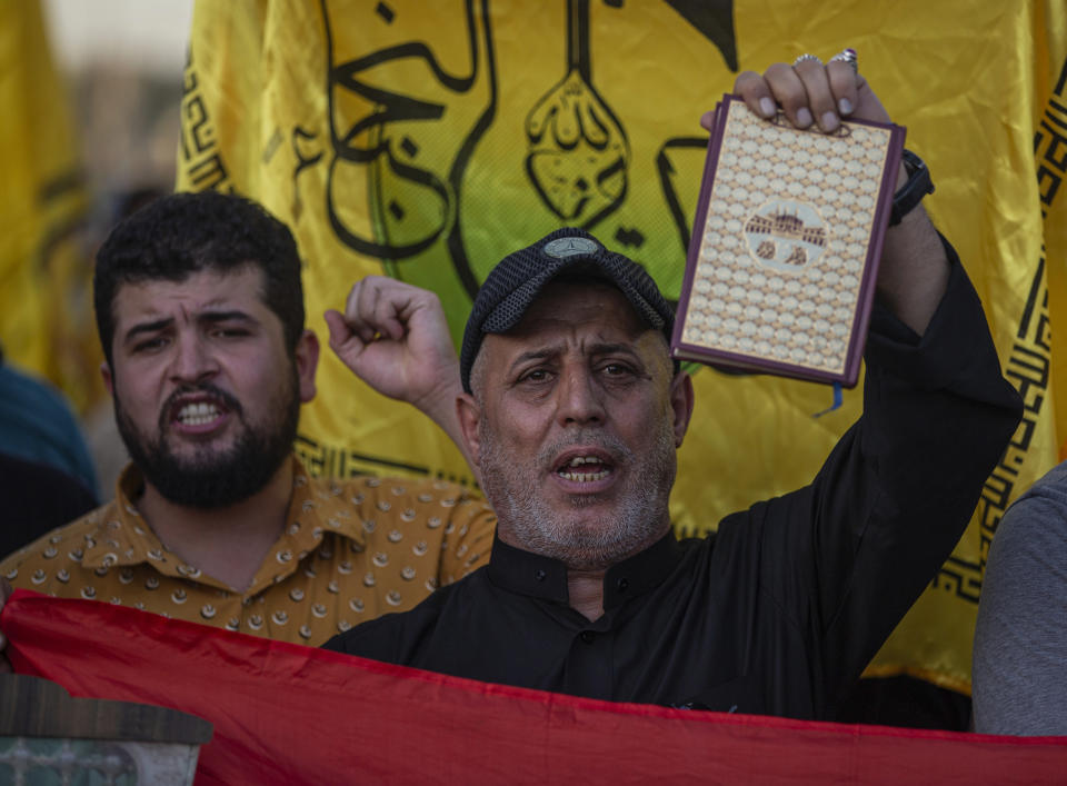 An Iraqi raise copy of the Quran, Muslims' holy book, during a protest in Tahrir Square, Thursday، July 20, 2023 in Baghdad, Iraq. The protest was in response to the burning of Quran in Sweden. (AP Photo/Adil AL-Khazali)