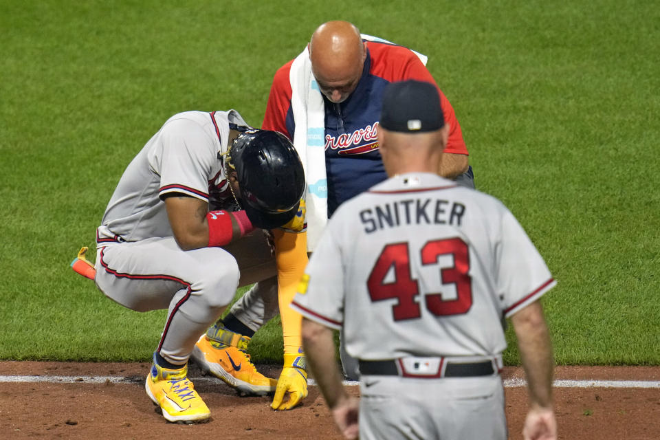 Atlanta Braves' Ronald Acuña Jr., left, is checked by a team trainer and manager Brian Snitker (43) after being hit by a pitch from Pittsburgh Pirates' Colin Holderman during the sixth inning of a baseball game in Pittsburgh, Tuesday, Aug. 8, 2023. (AP Photo/Gene J. Puskar)