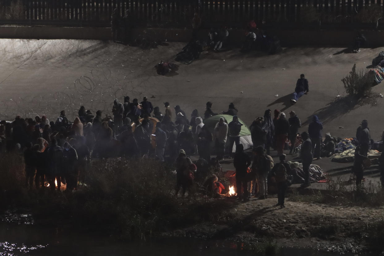 Migrants gather near a camp fire near the U.S.-Mexico border as seen from Ciudad Juarez, Mexico, Tuesday, Dec. 20, 2022. (AP Photo/Christian Chavez)