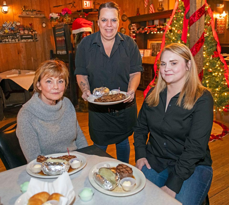 Coach-N-Four owners Donna Guilford and Rachel Thrower are served the restaurant's signature steaks by Cicey Roper on Wednesday, Nov. 29, 2023. The longtime Pensacola restaurant has been serving Pensacola and race fans since 1979.