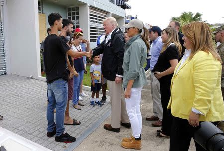 U.S. President Donald Trump talks with residents as first lady Melania Trump (C) and U.S. Rep and Resident Commissioner of Puerto Rico Jenniffer Gonzalez (R) look on as the president visits areas damaged by Hurricane Maria in Guaynabo, Puerto Rico, U.S., October 3, 2017. REUTERS/Jonathan Ernst
