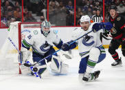 Vancouver Canucks goaltender Thatcher Demko (35) keeps his eye on the puck as teammate Luke Schenn (2) deflects a shot while taking on the Ottawa Senators during the second period of an NHL hockey game, Wednesday, Dec.1, 2021 in Ottawa, Ontario. (Sean Kilpatrick/The Canadian Press via AP)