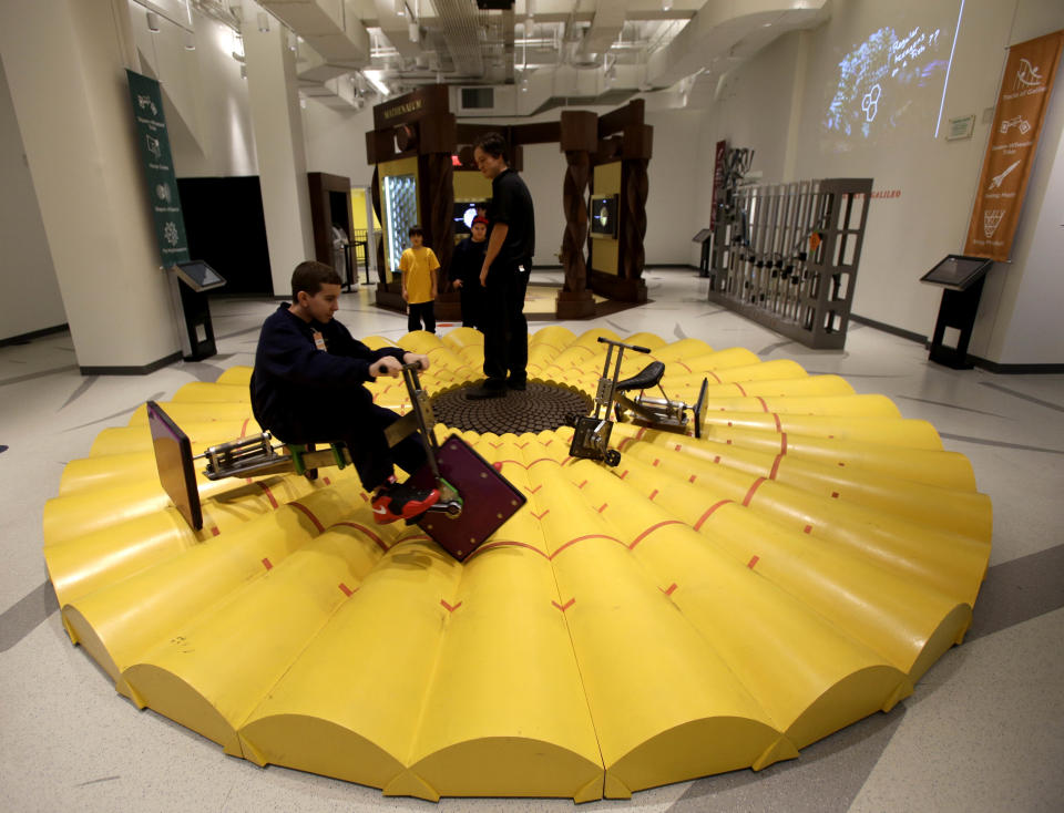 A visitor to the new National Museum of Mathematics rides a tricycle with square wheels in New York, Monday, Dec. 17, 2012. The museum is aimed at kids aged 8 to 13, and curators have given the place a playground feel. The 40 exhibits include a "wall of fire" made up of laser lights that teaches kids about geometry and a square-wheeled tricycle that still manages to produce a smooth ride thanks to a wavy track. (AP Photo/Seth Wenig)