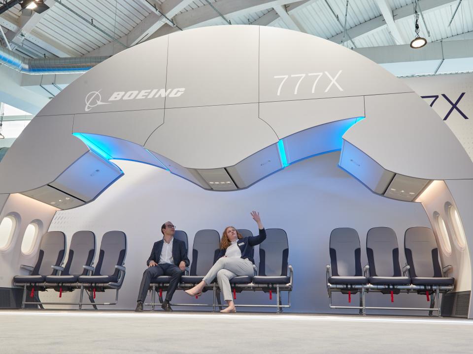 Two people sitting in 10-abreast Boeing 777X cabin mockup.