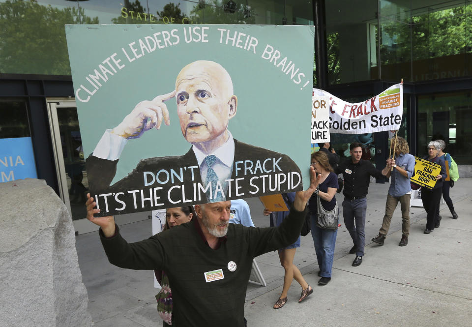 FILE - In this May 19, 2014, file photo, Richard Gray joins others in a demonstration calling on Gov. Jerry Brown to end hydraulic fracturing for oil and gas, in Sacramento, Calif. Brown was frequently criticized by environmental groups for not banning fracking or oil drilling. Gov. Gavin Newsom fired state Oil and Gas Supervisor Ken Harris, Thursday, July 11, 2019, saying he did not "exercise consistency" with the governor's opposition to hydraulic fracturing. (AP Photo/Rich Pedroncelli, File)