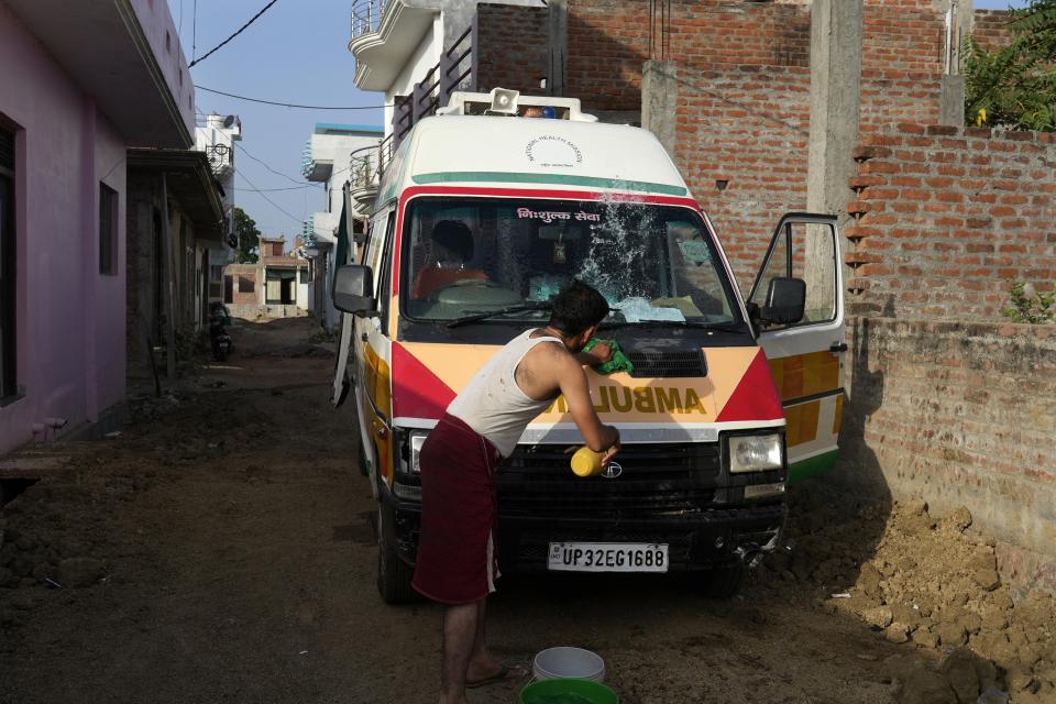 Sunil Kumar Naik cleans his ambulance before starting his shift in Banpur in the Indian state of Uttar Pradesh, Sunday, June 18, 2023. Ambulance drivers and other healthcare workers in rural India are the first line of care for those affected by extreme heat. (AP Photo/Rajesh Kumar Singh)