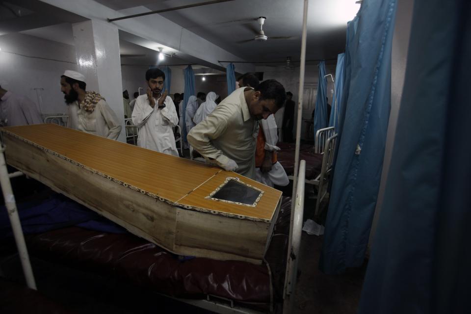 People stand near coffin of a victim, who was killed in a bomb blast, at a hospital in Peshawar