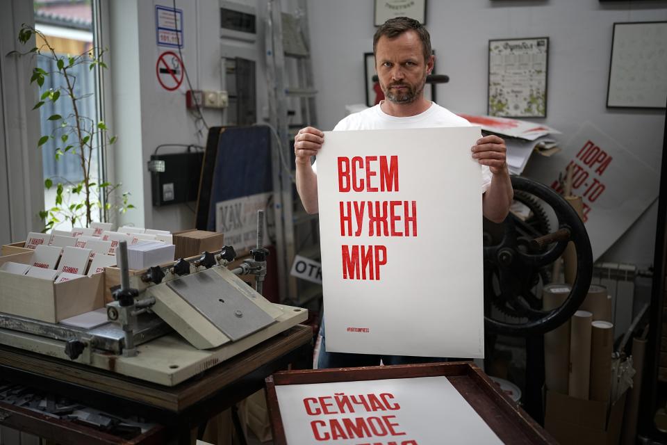 Sergei Besov, a Moscow-based print artist poses for a photo holding a poster reads "Everyone needs peace" in his workshop in Moscow, Russia, Tuesday, July 5, 2022. Besov felt he couldn't stay silent after Russia sent its troops into Ukraine and started printing posters about it. Despite a massive government crackdown on such acts of protest, some Russians have persisted in speaking out against the invasion — even in the simplest of ways. (AP Photo/Alexander Zemlianichenko)