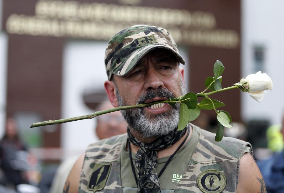 Un hombre sostiene una rosa con los dientes antes de colocarla en un altar improvisado afuera de la Escuela de Cadetes de Policía General Francisco de Paula Santander, un día después de que un coche bomba explotara en esa academia, en Bogotá, Colombia, el viernes 18 de enero del 2019. (AP Foto/John Wilson Vizcaino)