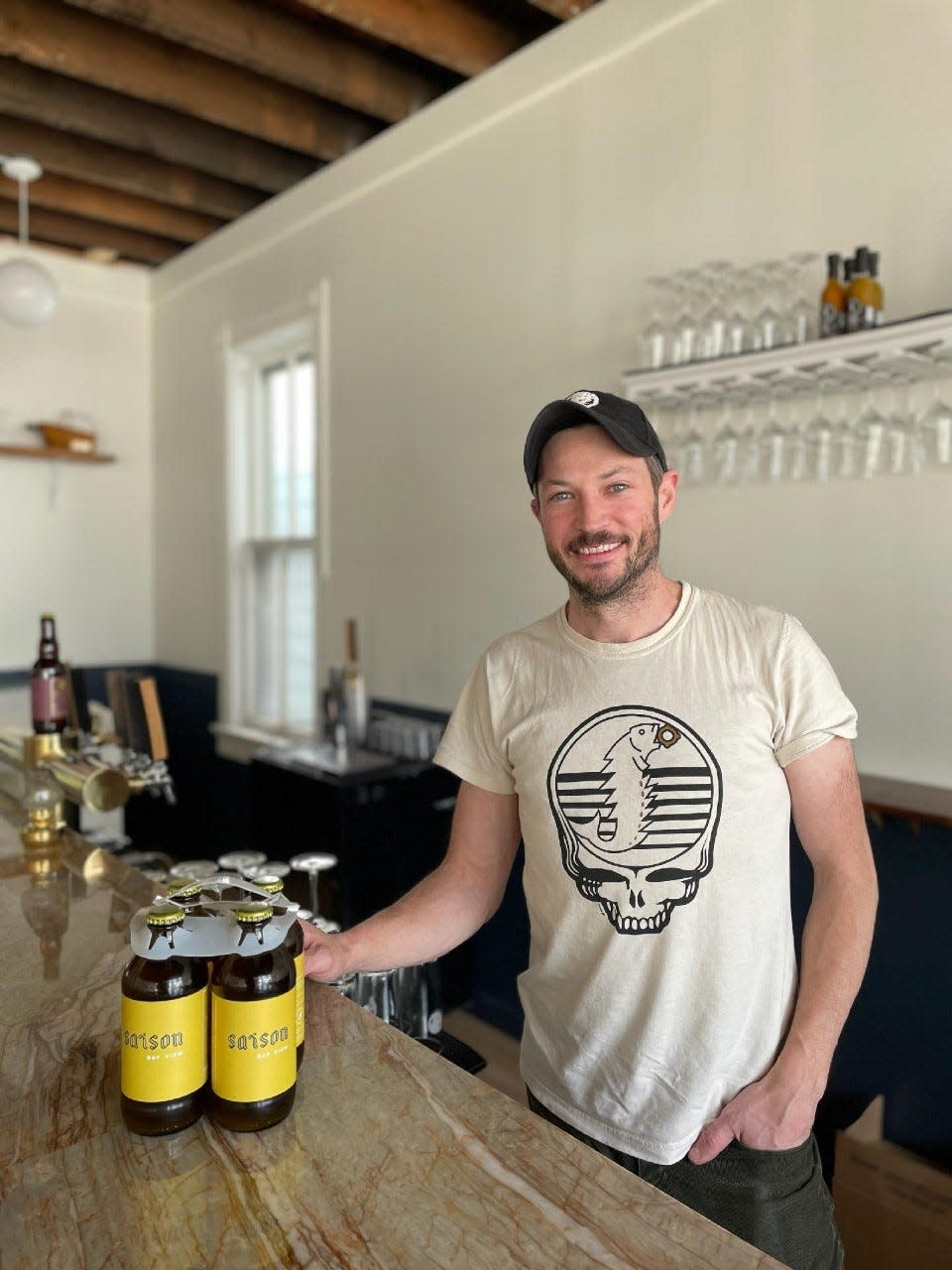Rob Brennan, who owns Supermoon brewery with his wife, Maria Keegan, stands behind the bar in the century-old building that once held a general store. Saison (shown) is one of the beers he makes.