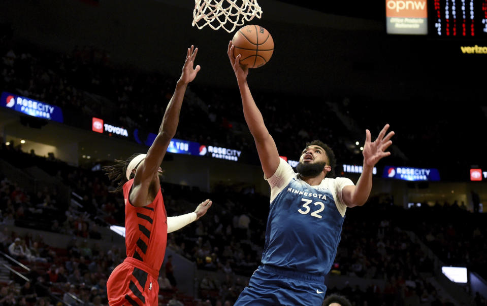 Minnesota Timberwolves center Karl-Anthony Towns, right, drives to the basket against Portland Trail Blazers forward Jerami Grant during the first half of an NBA basketball game in Portland, Ore., Tuesday Feb. 13, 2024. (AP Photo/Steve Dykes)