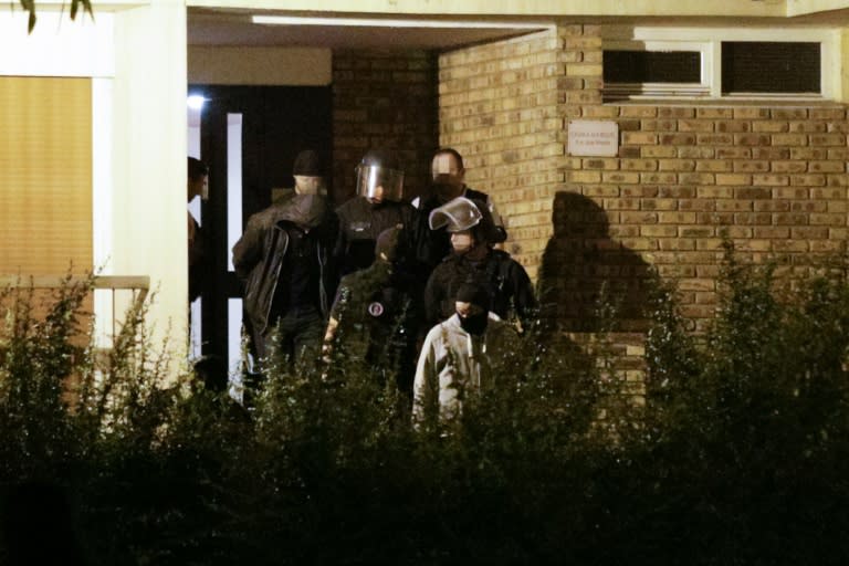 A handcuffed man is taken out of the building in Boussy-Saint-Antoine south of Paris on September 8, 2016 where female suspects, said to have been planning new acts of violence, were arrested