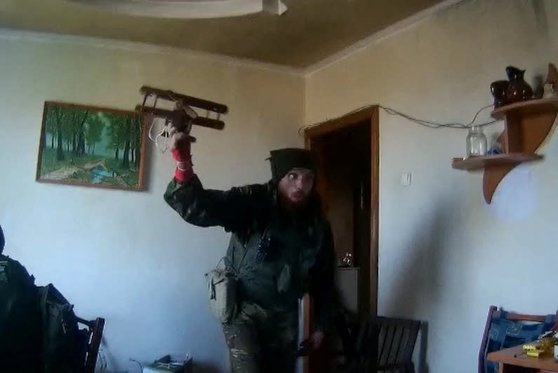 Screengrab from video obtained by Reuters shows a fighter from the BARS-09 volunteer force of the Russian military playing with a toy aircraft he found in an apartment in Balakliia