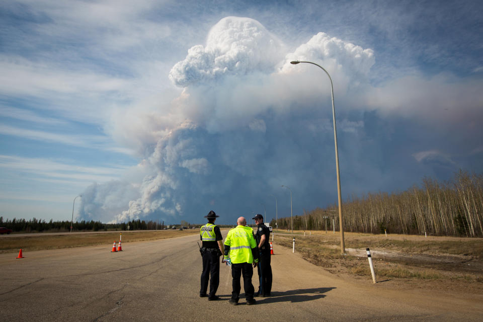 Officers look on as smoke from Fort McMurray's raging wildfires billow into the air after their city was evacuated, May 4, 2016. REUTERS/Topher Seguin