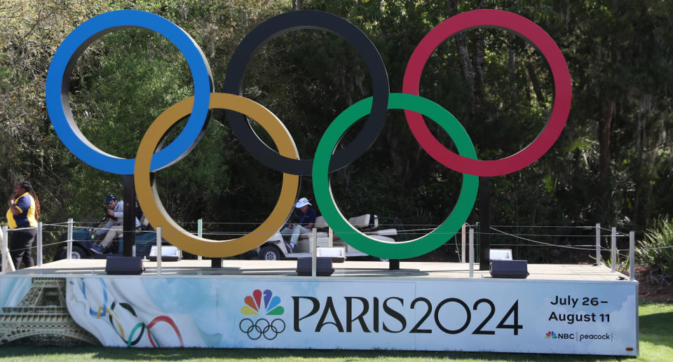Olympic rings displayed above a Paris 2024 sign.