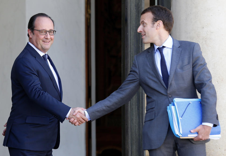 FILE - In this July 31, 2015 file photo, French President Francois Hollande, left, shakes hands with then French Economy minister Emmanuel Macron at the Elysee Palace in Paris. From his high school romance with a teacher to his recent ambition to become president, Macron was known for his intelligence, listening capacity and tenacity _ assets that could help propelling him the country's next leader (AP Photo/Jacques Brinon, File)