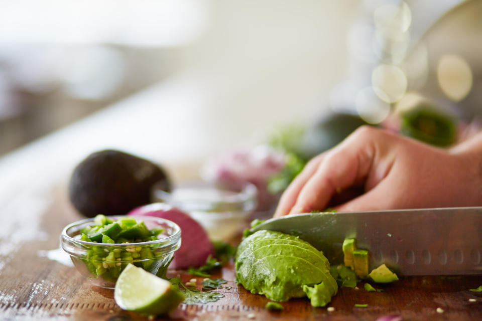 cutting avocado with skin removed and dicing to prepare for guacamole recipe