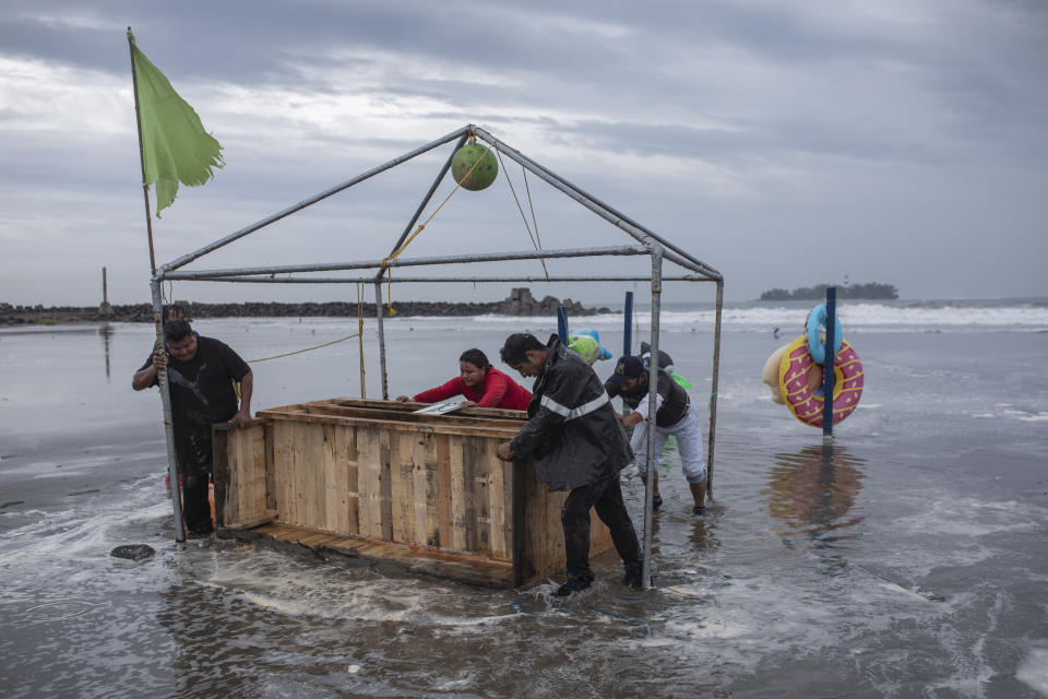 Varias personas retiran su puesto de la playa el viernes 20 de agosto de 2021, en Boca del Río, México, en preparación para la llegada del huracán Grace. (AP Foto/Félix Márquez)